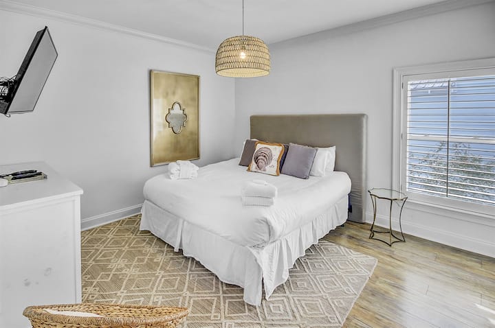 Dormitorio tamaño king del segundo piso: disfruta de la comodidad en nuestro dormitorio del segundo piso adornado con una lujosa cama tamaño king y un baño privado. Hay una cómoda, un armario y una gran televisión montada. 