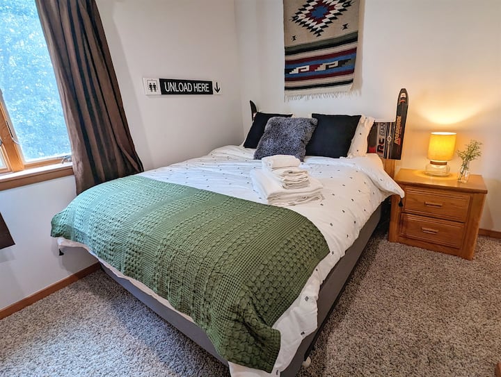 El dormitorio tamaño queen tiene una cama tamaño queen, cortinas oscurecedoras, armario y vestidor pequeño.