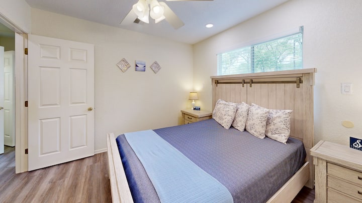 Sleep peacefully in this bright and cozy bedroom featuring plush bedding and soft lighting—ideal for restful nights after exploring Gruene.