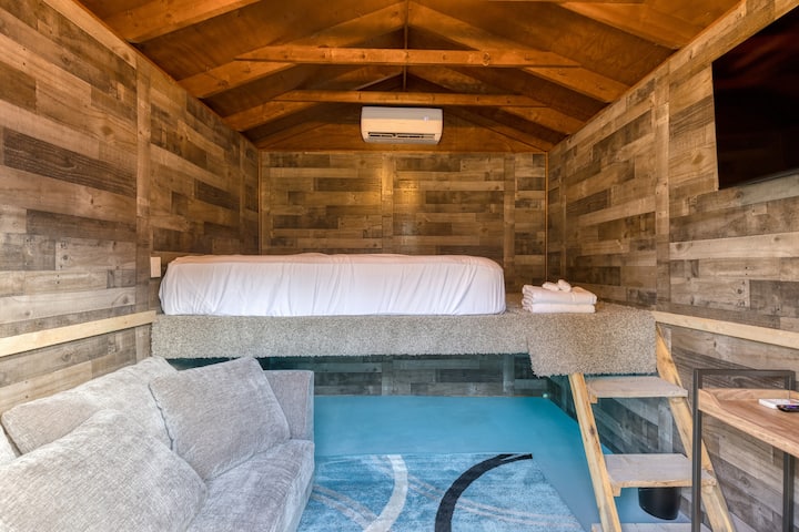 يتميز بيت الدخان المحول بسرير كبير وأريكة وتلفزيون.