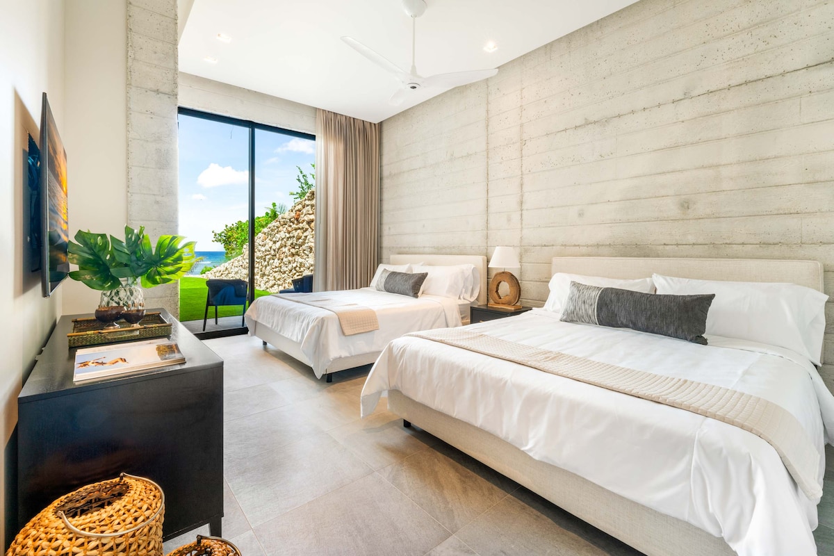 Suite 7 en el nivel inferior con dos camas tamaño king, vistas al mar, televisión y acceso a la terraza de la piscina y a la playa. 