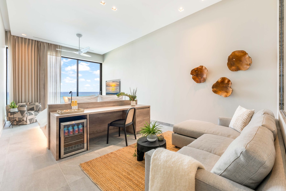 Suite 2 con cama tamaño king, vistas al mar, televisión, escritorio y silla con centro de bebidas. Idéntico a la suite 1, pero sin acceso a la ducha al aire libre. 