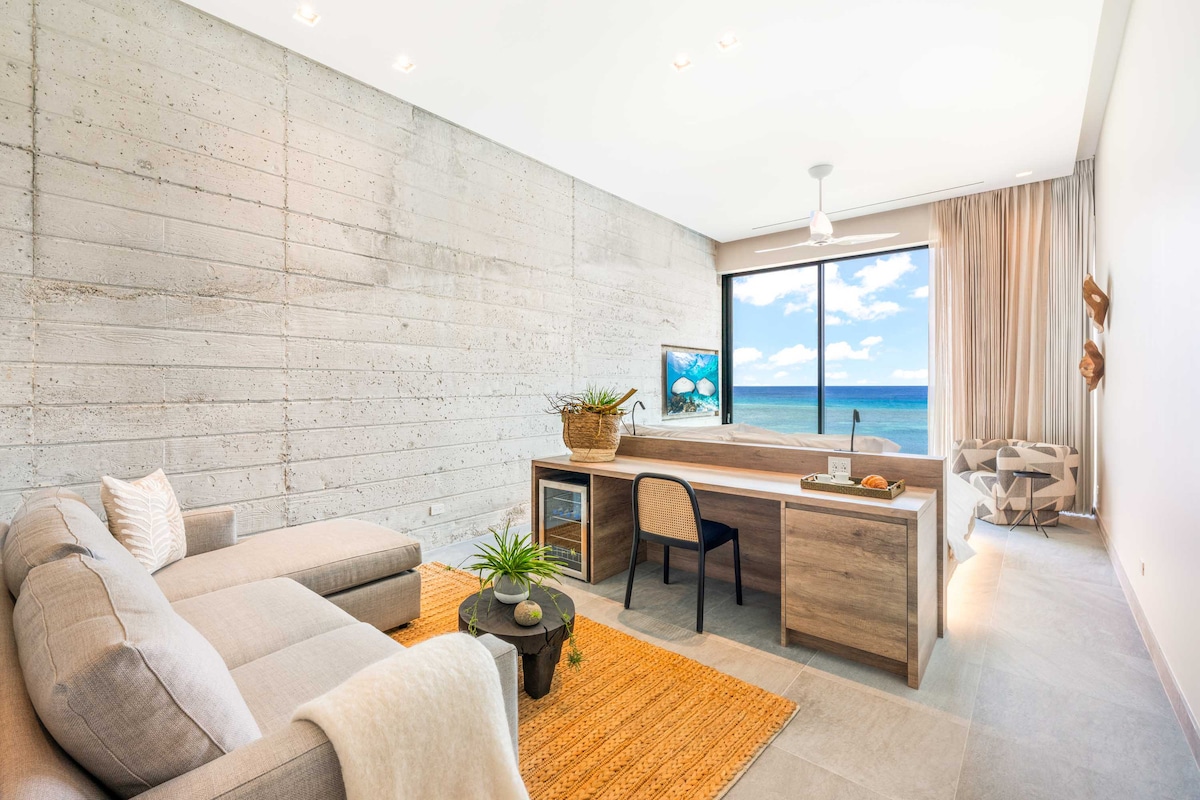 Suite 1 con cama tamaño king, vistas al mar, televisión, escritorio y silla con centro de bebidas. 