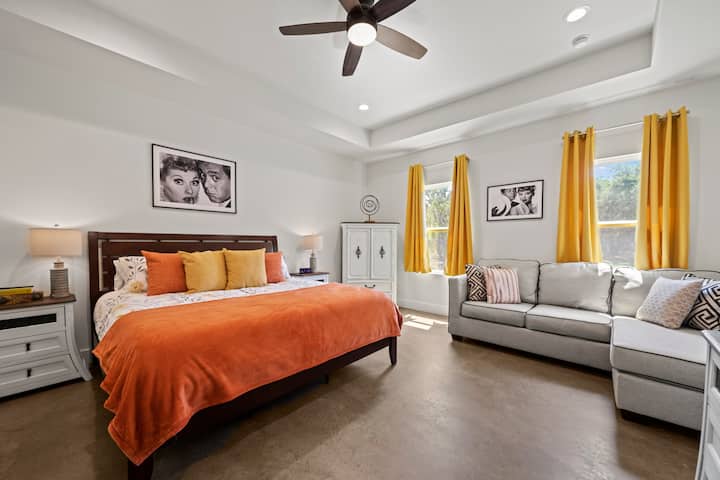 Спалнята на снимката е уютна и приветлива, с топла цветова палитра и много естествена светлина.