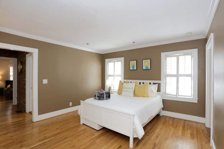 Съвременна спалня с двойно легло, елегантен бял диван и полирани дървени подове.