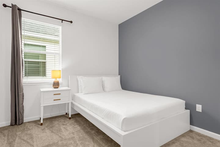 Queensize-Schlafzimmer mit sauberer weißer Ästhetik und reichlich Beleuchtung