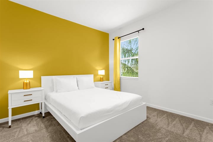 Helles Queensize-Schlafzimmer mit fröhlicher gelber Akzentwand