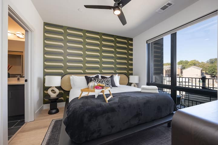 Chumba cha kulala cha msingi kilicho na kitanda cha King, runinga janja, madirisha ya sakafu hadi dari na bafu la ndani.