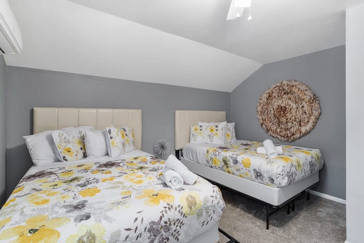 Two plush beds with floral bedding stand against soft gray walls, offering a cheerful yet calming retreat.