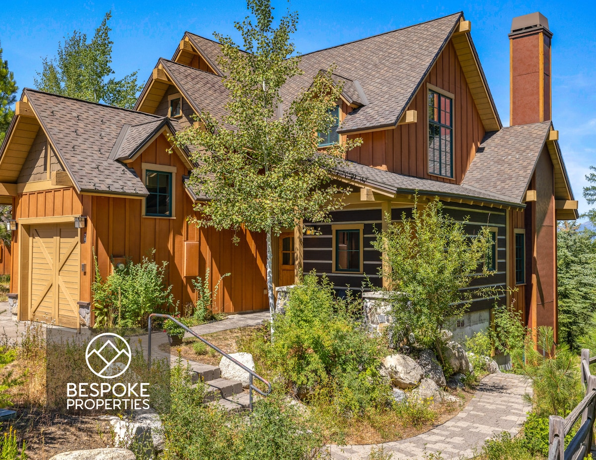 The exterior of the townhome showcases a blend of rustic and modern architecture, featuring warm wood and stone accents. Stairs lead to the entrance, surrounded by natural landscaping and trees, creating a serene atmosphere in the Clearwater neighborhood.