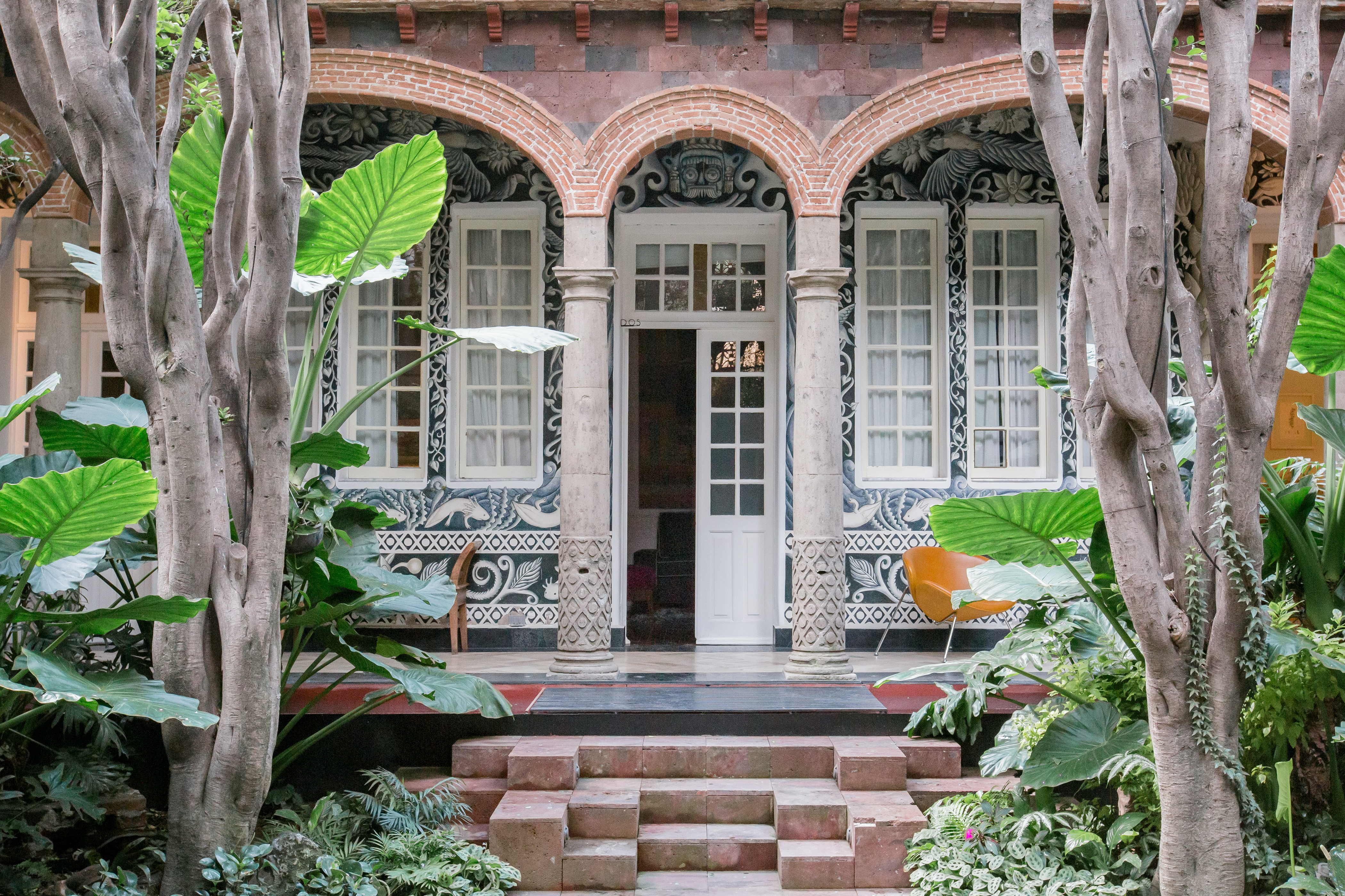 Recámara privada e independiente frente a un patio con jardín y murales.